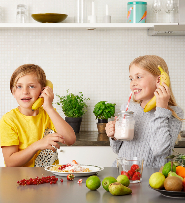 Barn dricker glass och pratar över banantelefon